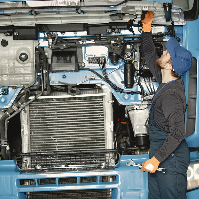 Al Saha technician inspecting a truck engine bay for electrical faults at the Musaffah workshop, Abu Dhabi