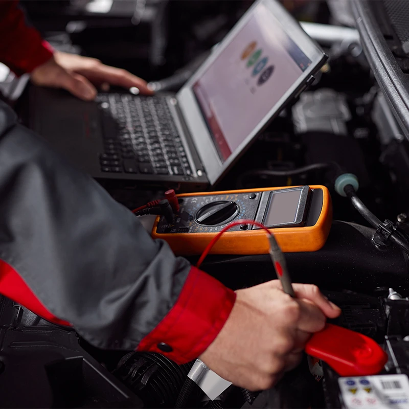 Technician performing an ECU remap using laptop diagnostic software and test equipment on a heavy vehicle